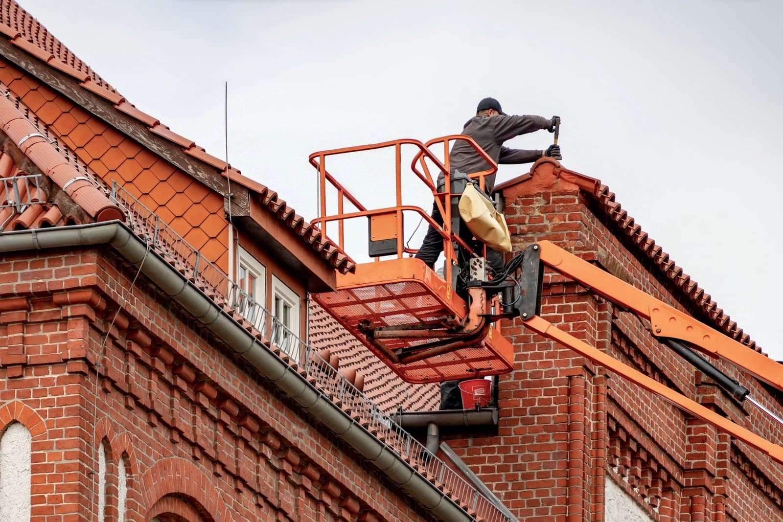Intervention sur la gouttière d'une maison en briques depuis une nacelle