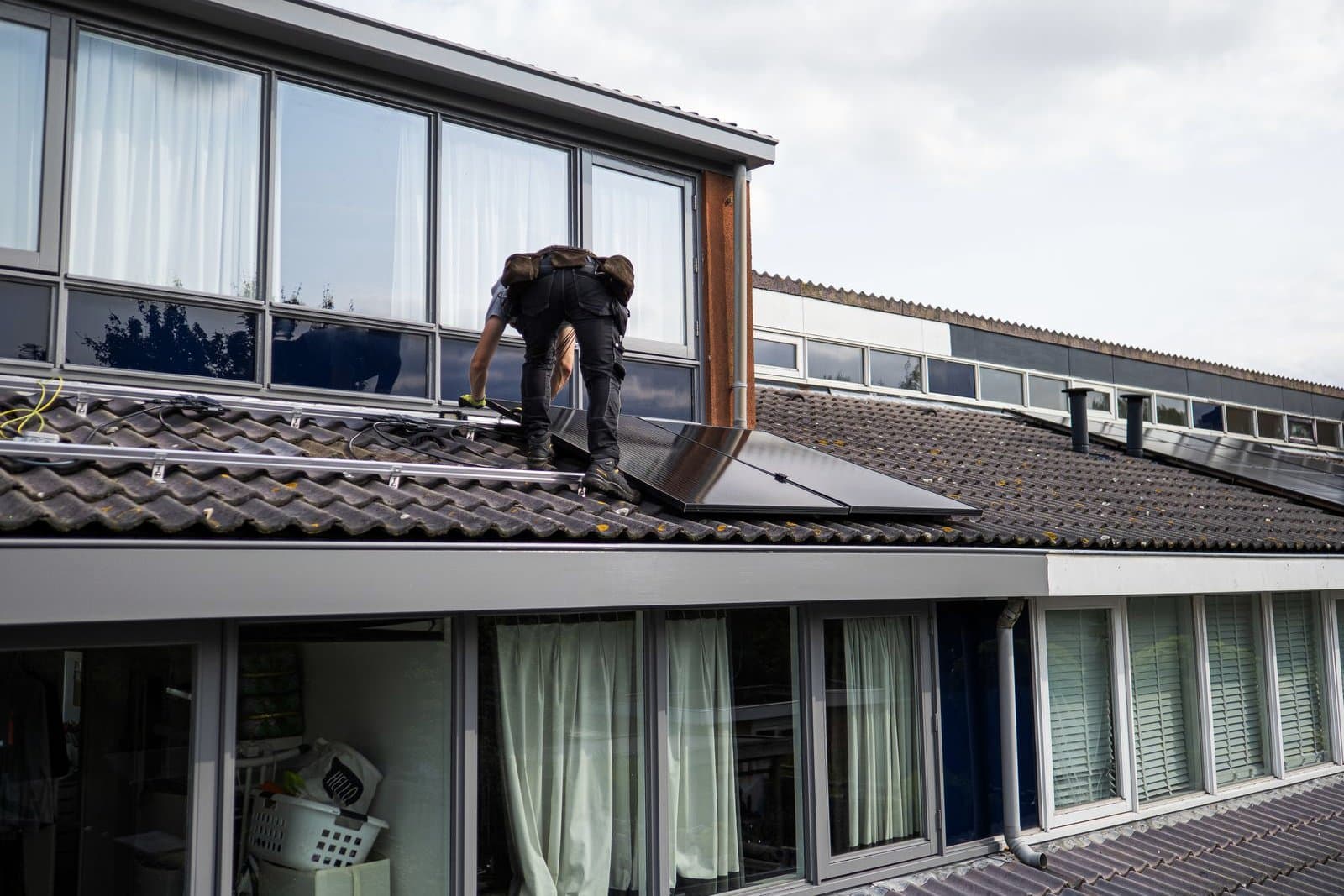 Technicien intervenant sur des panneaux solaires posés sur une toiture en tuiles